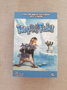 photograph of a rulebook for the game Hey! That's my fish. The cover shows a cartoon penguin standing on an ice-floe, clutching some fish, while another penguin is raging in the background