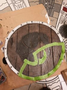 photo of the shield with masking tape outlining painting lines