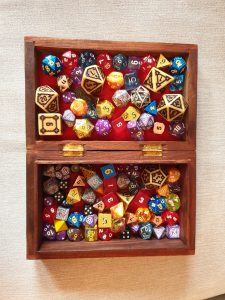 an open wooden box filled with polyhedral dice used for role playing games