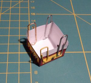 The sides of the gondola glued together to make a square box. Glue points held together using paper clips.