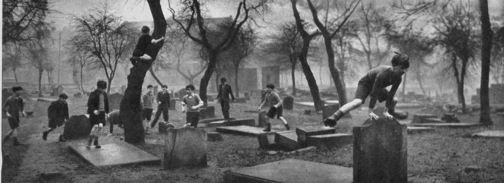 A group of children from the Gorbals play amongst the gravestones of the Corporation Burial Ground in Rutherglen Road, one of the few areas of greenery in the district. 1948. taken by Bert Hardy
