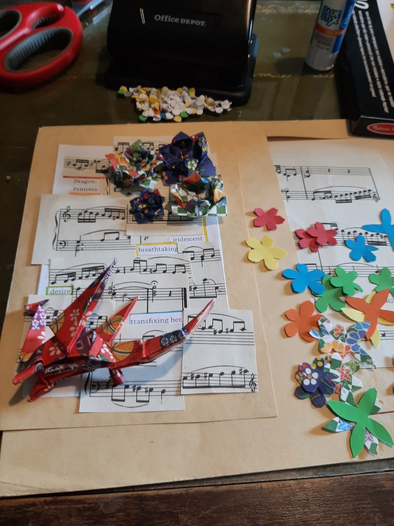 The image shows component pieces of the sheet music and poetry, origami flowers and dragon, and small paper flowers in multiple colours.