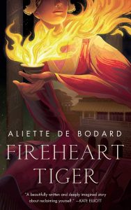 Image shows the cover of Aliette De Bodard's Fireheart Tiger. The cover's central image is a woman in a beautiful red and gold robe - reminiscent of a fire. In her hands there is a tea cup out of which a glorious set of flames blazes. Only the chin, mouth and nose of the woman's face is visible, along with the edges of a gold headdress. Faded into the right sleeve of the role there is an overlaid image of siheyuan style buildings. Behind the woman is the fade image of 4 pillars.