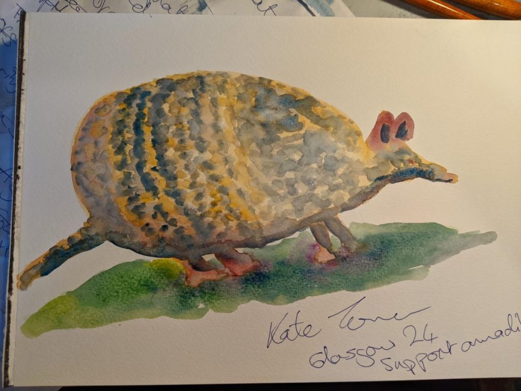 Armadillo painted in watercolours in yellows and greys.