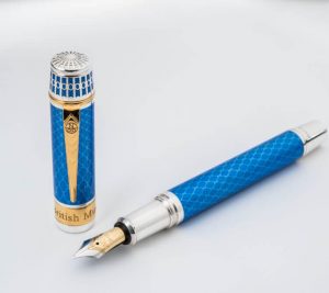 photo of a fountain pen with a silver and blue enamel body, its cap off and standing on its end next to the pen