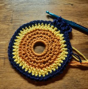 Finished orange and yellow crochet sun with the first row of navy background added.
