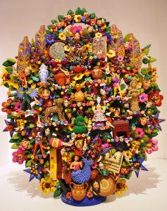 A Tree of Life made up of various household items and toys, as well as plastic flowers, creating a large statue.