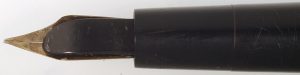 Close-up of the top third of a black, slightly worn, fountain pen with a gold nib.