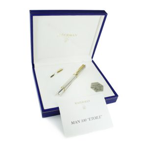 A blue case opened wide, with a silver and gold fountain pen and secondary nib sat on a white cloth inside the box. Propped up on the front of the case is a card that reads 'Man 100 "Etoile"'.