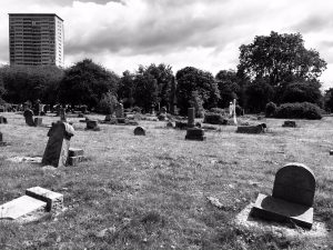 Landscape shot in black and white of the Southern Necropolis in Glasgow - tower blocks in the distance, gravestones in the fore view