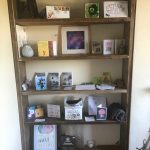 Photograph of bookcase full of art and tokens of fandom.