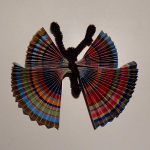 A butterfly made from striped wrapping paper, using two pieces that are plied so they fan out to both sides to make the wings. The body is a brown chenille stick holding the paper in place and forming the antennae