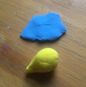 Top: flat blue piece of clay, tapered towards the left. Bottom: Yellow pear-shaped piece with the tip to the left.