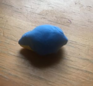 Blue sheet of clay wrapped around the pear-shaped yellow form.
