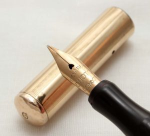 photograph of a fountain pen, its tip balanced on its golden cap