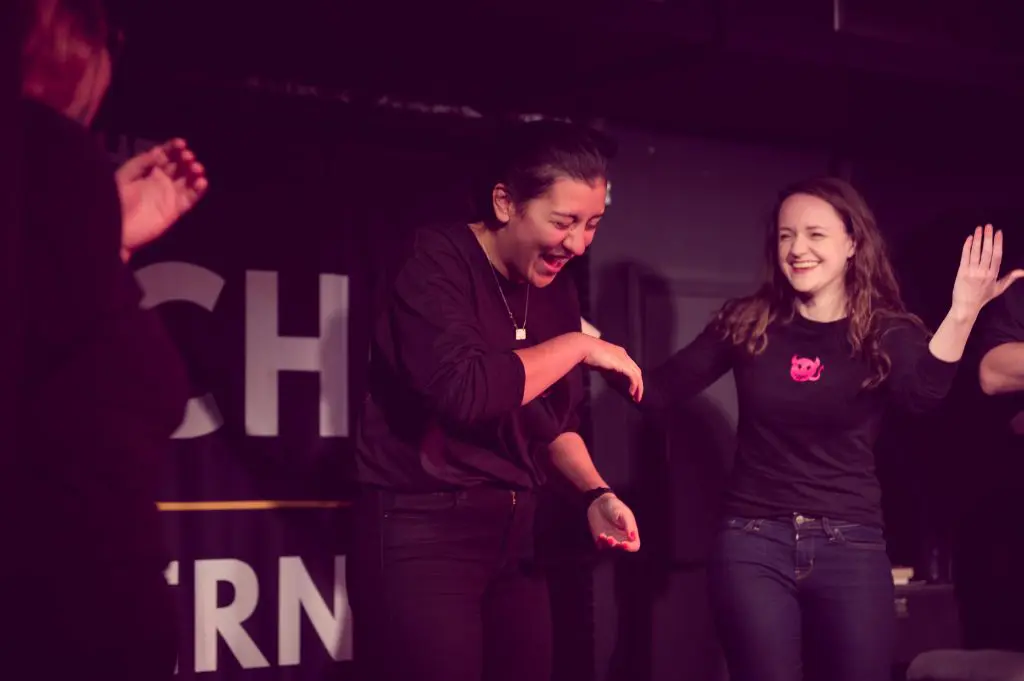 Two people are seen laughing, fully engaged in the humor of a comedy show.