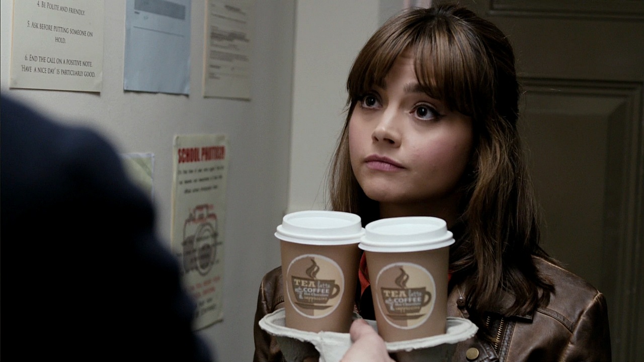 Clara (Jenna Coleman) holds two cups of take-out coffee.”