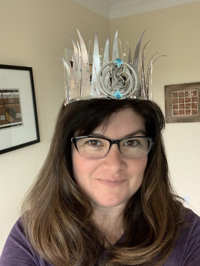 Sara Felix looking into the camera, wearing glasses and a metal crown.